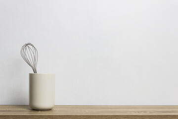 A silver whisk on table over the light background. 