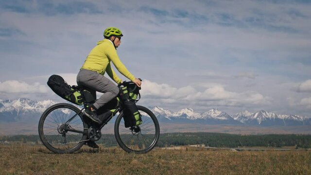 The man travel on mixed terrain cycle touring with bikepacking. The traveler journey with bicycle bags. Sport tourism bikepacking.