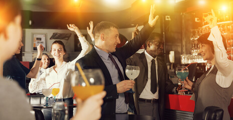 Cheerful businessman with female colleague dancing and drinking alcohol, having fun at office party...
