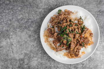 Top view Rice topped with stir-fried beef and holy basil (Pad Ka Prao) popular Thai street food on the concrete table