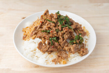 Close up Rice topped with stir-fried beef and holy basil (Pad Ka Prao) popular Thai street food. on the wooden table