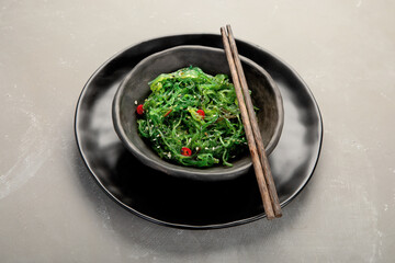 Wakame seaweed with sesame and chilli on gray background. Asian food concept.