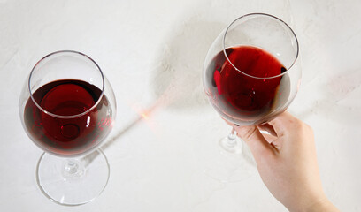 Young woman holding glass of red wine on white background. Hand with black polish.