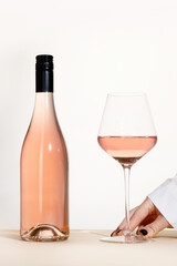 Young woman holding glass of rose wine on white background. Hand with black polish.