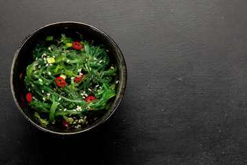Wakame seaweed with sesame and chilli on gray background. Asian food concept.