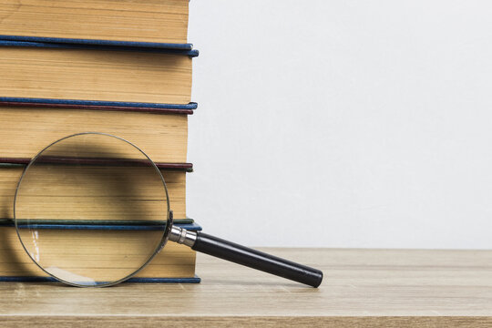 A magnifying glass and books on table.