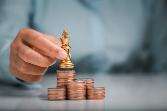 Human hand holding gold king chess on stack of coins, money power or saving money, financial growth, business finance wealth and success concept.