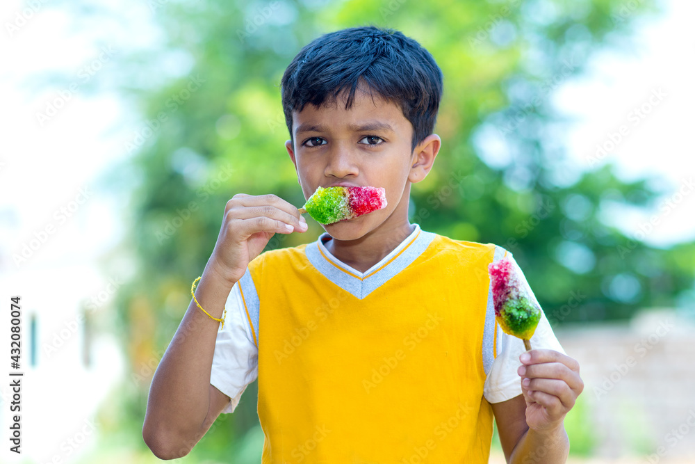 Sticker selective focus of a little indian boy eating flavored colorful ice gola