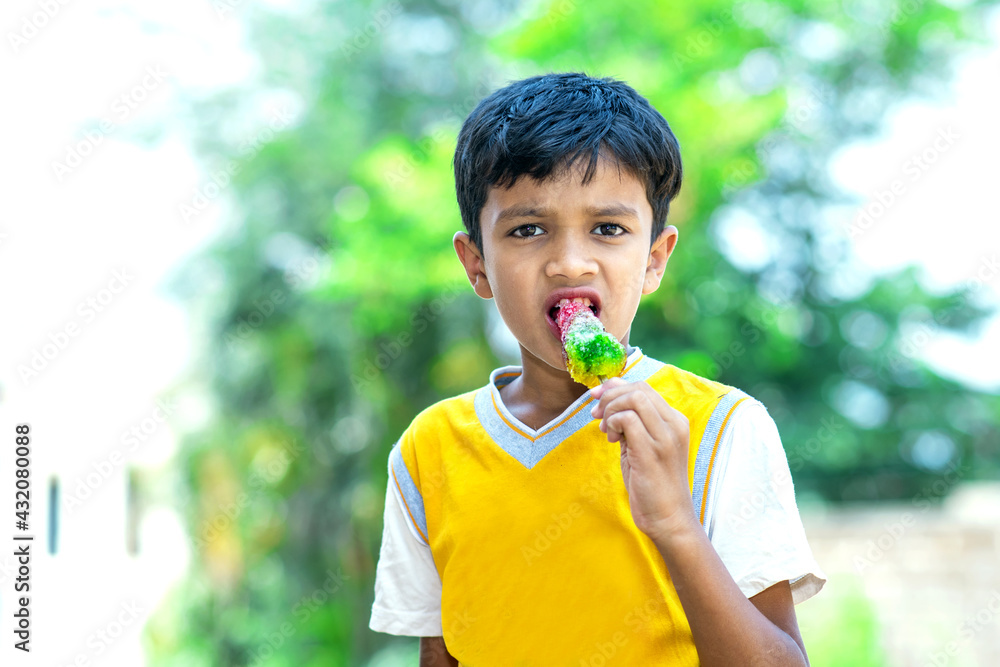 Sticker selective focus of a little indian boy eating flavored colorful ice gola