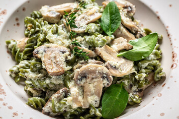 Penne pasta with white mushrooms in creamy sauce on dark table. italian Penne pasta with champignon mushroom. Spring pasta with green vegetables. top view