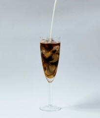 milk pouring into iced coffee swirling