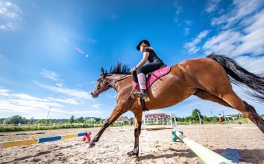 Dziewczyna skacze przez przeszkodę konno na obozie jeździeckim, summer camp, jazda konna, wakacje letnie na koniach - obrazy, fototapety, plakaty