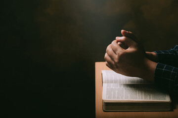 Hands of praying young man and Bible on a wooden desk background.man join hands to pray and seek the blessings of God, the Holy Bible. - obrazy, fototapety, plakaty