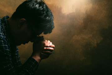 Religious man praying to God resting his chin on his hands.His hands are praying for God's blessings.