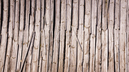 Gray natural background from old, sun-aged wooden boards, close-up fragment of a wooden barn wall