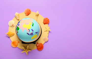 Globe with hat and seashells on color background