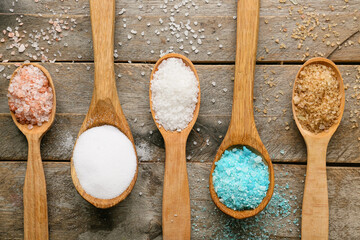 Naklejka na ściany i meble Spoons with different salt on wooden background