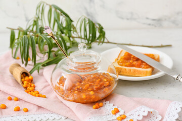 Jar of healthy sea buckthorn jam with bread on table