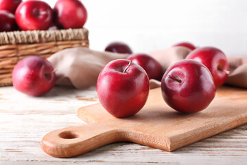 Board with fresh red apples on wooden background