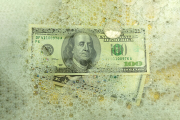 Money laundering concept, dollars in soapy water