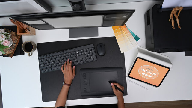 Above view of graphic designer working with graphic tablet at modern workspace.