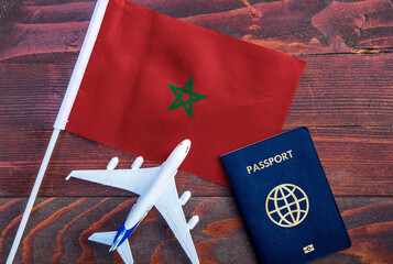 Flag of Morocco with passport and toy airplane on wooden background. Flight travel concept. 