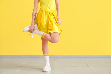 Stylish young woman near yellow wall
