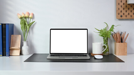 Mock up laptop computer, coffee cup, books, houseplant and pencil holder at home office.