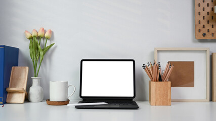 Mock up computer tablet, coffee cup and pencil holder on white table at home office.
