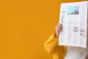 Obraz premium Stylish young man with newspaper on yellow background