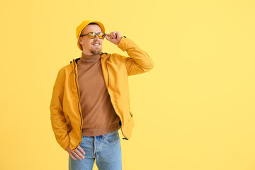 Stylish young man on yellow background