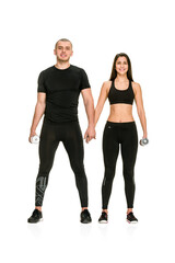Full length portrait of two healthy people in sportswear holding hands and posing with dumbbells