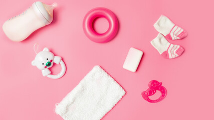 Top view of baby accessories with toy rattle on pink table background. A Girl Baby Shower. Mock up