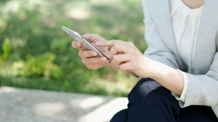 屋外でスマートフォンを操作するマスク姿のビジネスウーマン