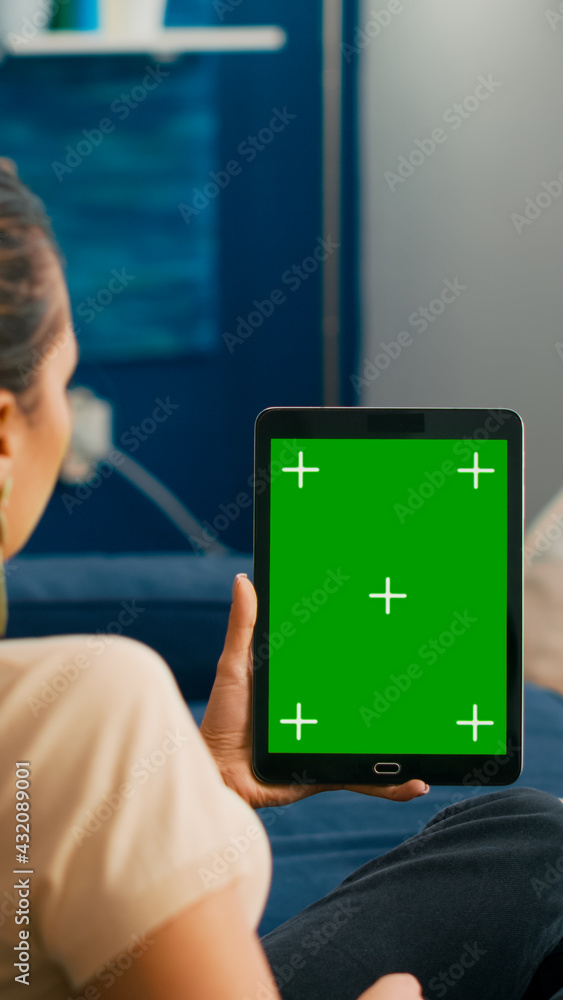 Aufkleber business woman looking at tablet computer with mock up green screen chroma key display sitting on so
