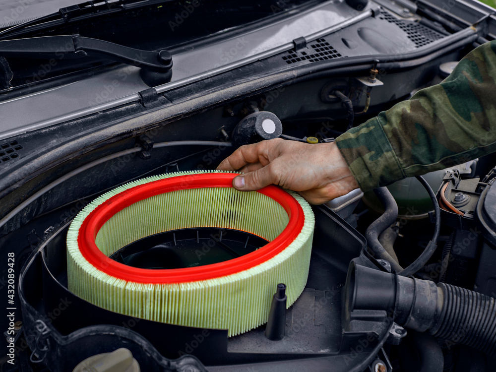 Wall mural man replaced air filter on engine of car