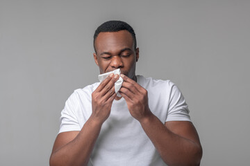 Unhappy man with handkerchief near nose