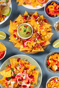 Nachos and various dips, top shot on a blue slate background