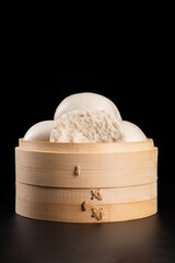 Chinese food steamed buns in bamboo on black background