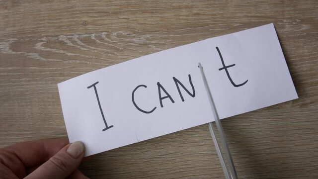 Female hands cut paper with written I CAN NOT word to turn it into I CAN