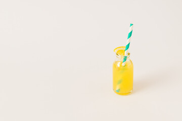 Fresh lemonade in small bottle with colorful straw on white background. Minimal summer concept.