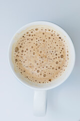 Top view of a creamy cappuccino coffe in a mug, isolated on a white background.