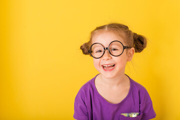 Little cute caucasian funny happy smile kid child baby girl with glasses glasses in purple T-shirt...