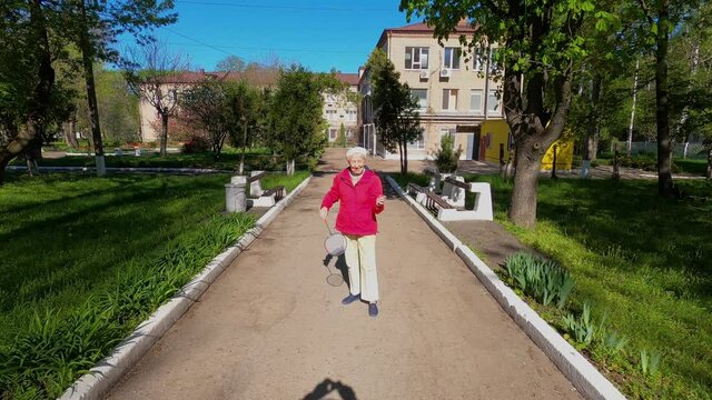 Senior Woman In The Meadow Playing Badminton At Park. Healthy Lifestyle Concept