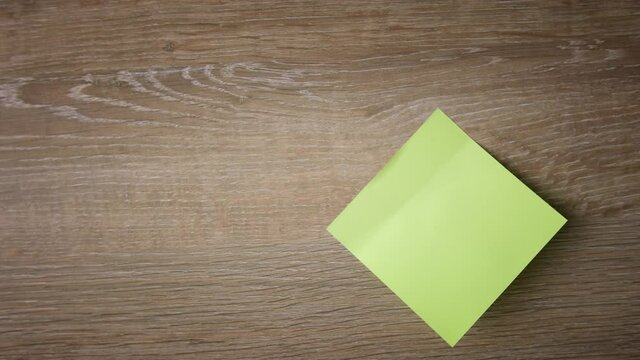 Female hand stick yellow note on wooden surface, write down LOVE YOU by red pen