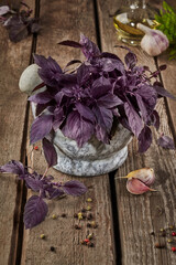 Purple basil in stone mortar with condiments on wooden table
