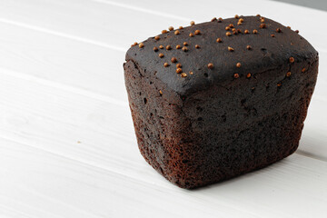 Loaf of rye bread on white wooden table