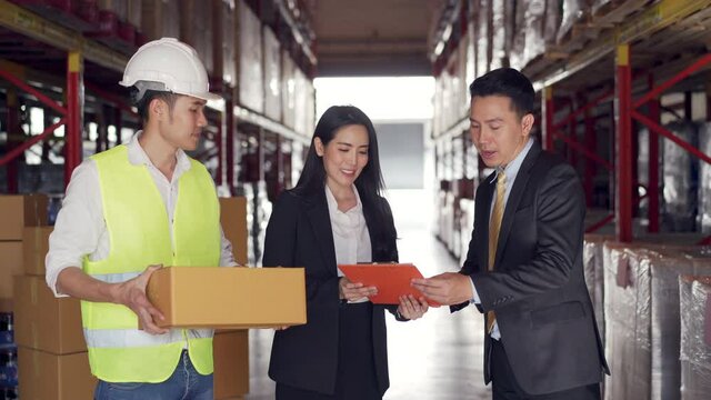 Group of Asian business people and warehouse worker discussion business project using digital tablet in distribution fulfillment center. eCommerce, B2B business, factory industry logistic concept.