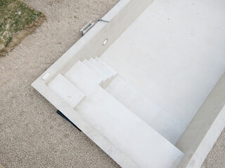 Drone photo of swimming pool in construction phase with gravel all around in a garden