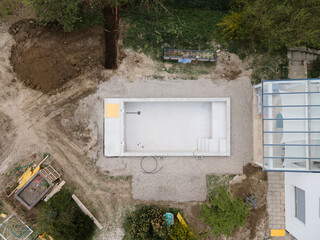 Drone photo of swimming pool in construction phase with gravel all around in a garden